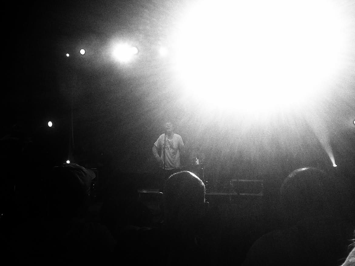 A singer alone on stage under a blinding white light